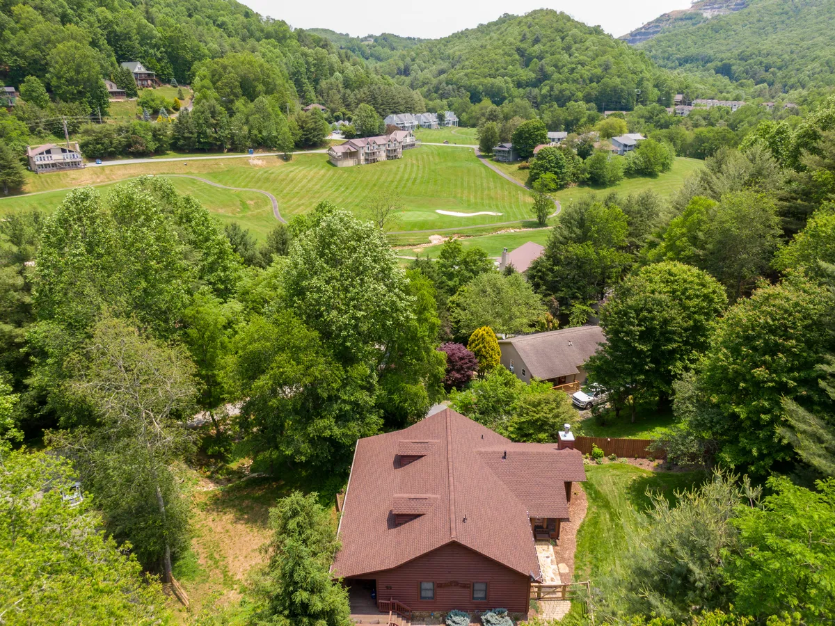 This image captures an expansive view of a verdant golf course, surrounded by lush trees and distant houses. The landscape offers a sense of openness and possibility, evoking activities like golfing, hiking, and picnicking—all mentioned in the section. The sunset and mountain backdrop hint at the region’s natural beauty and recreational opportunities.
