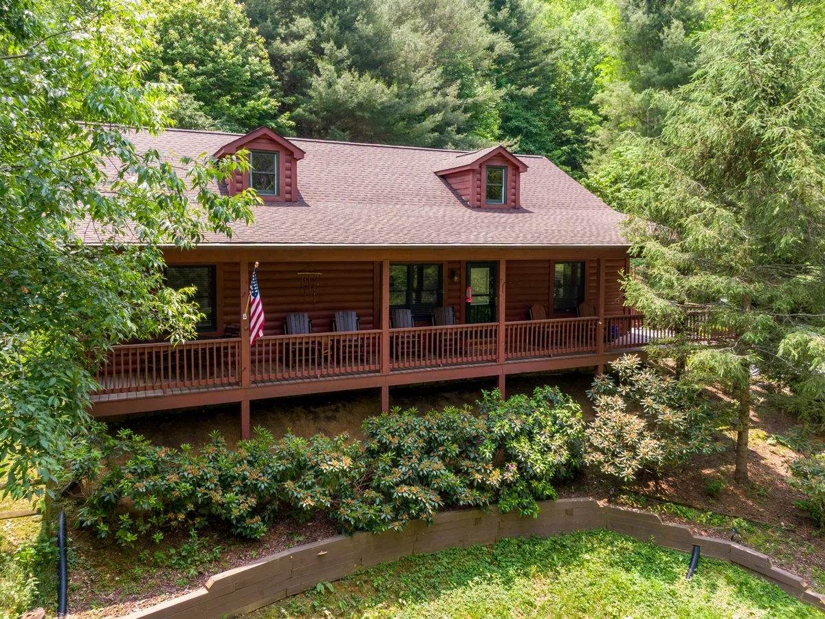 The front porch adorned with an American flag overlooks vibrant greenery, evoking a sense of welcome and comfort. The porch is set up for relaxing, nature watching, and enjoying gatherings.