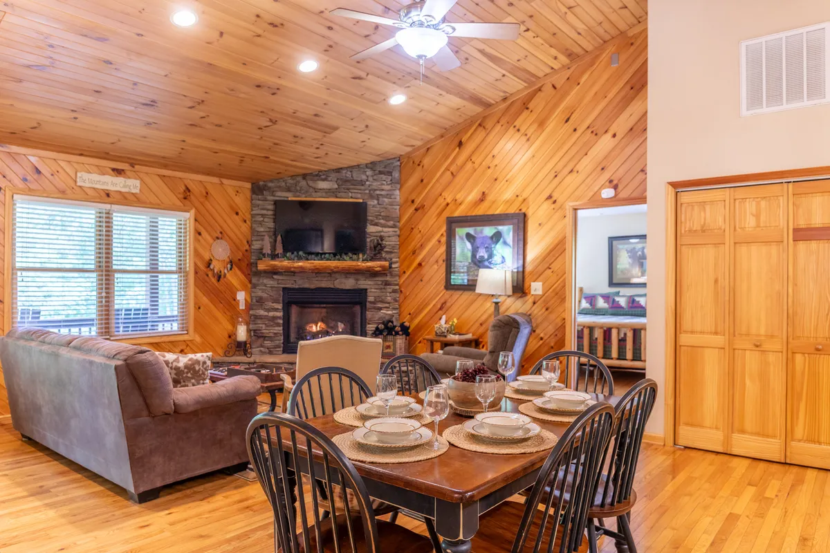 A cozy living area anchored by a fireplace, with a dining table, comfortable sofa, and tasteful wall art. The setting is warm, inviting, and perfect for unwinding after a day outdoors.