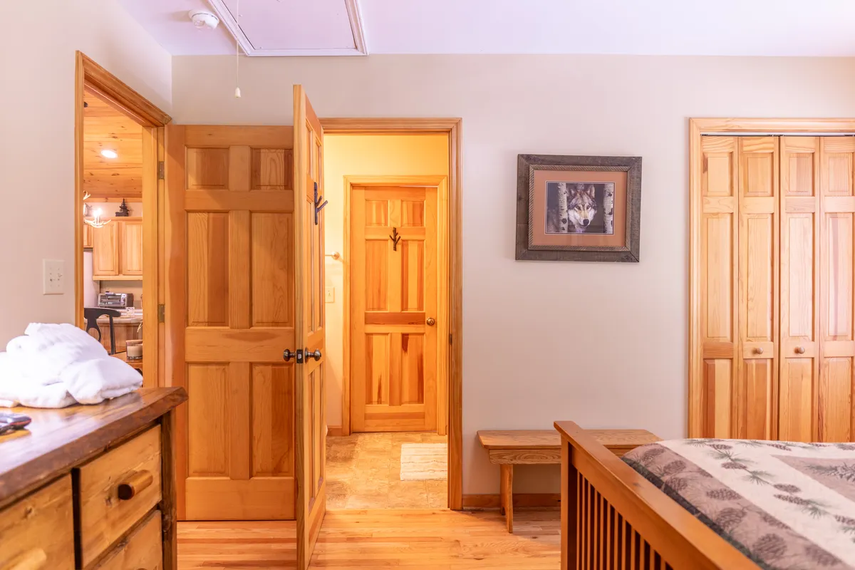 A bedroom with bedding adorned with nature prints, a wooden bench, and a striking framed wolf picture above wooden doors. The space feels both whimsical and comfortable, echoing the Wolf-themed bedroom described in the section.